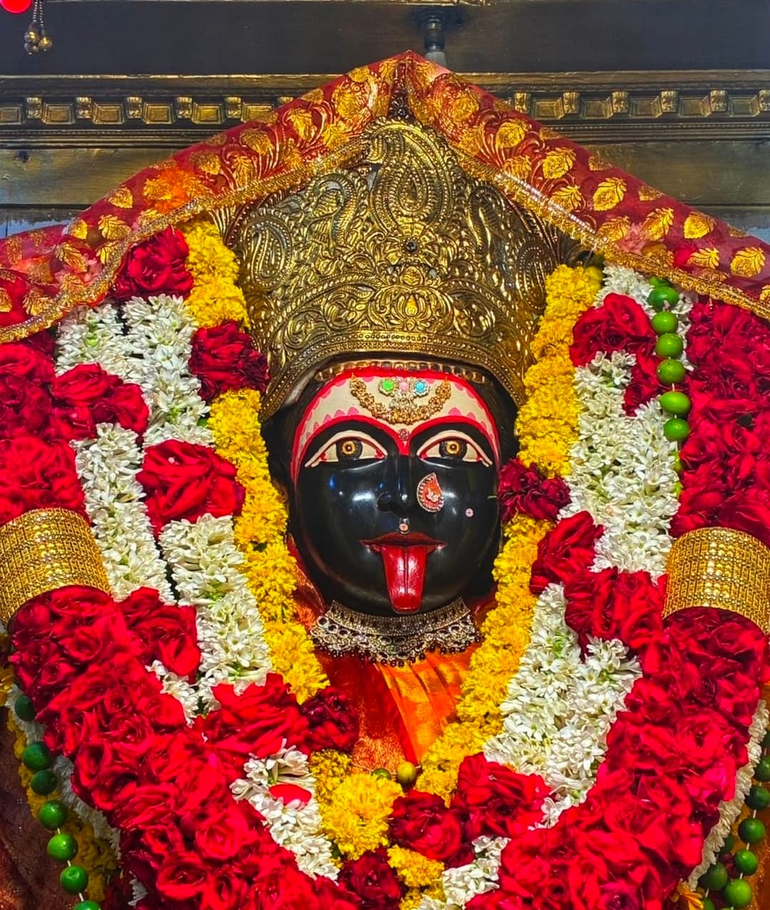 Idol of Goddess Kali with golden crown and flower garlands.