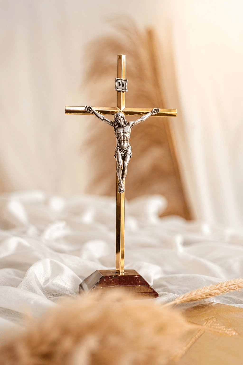High-resolution image of a gold and silver Jesus Christ crucifix with the INRI inscription on a wooden base, set against a soft beige background, perfect for Christian wallpapers and devotional artwork.